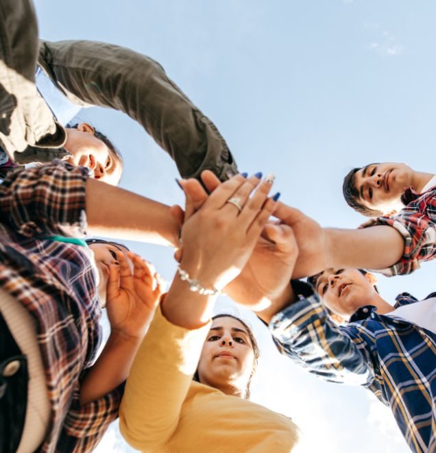 group of teenagers putting their hands together